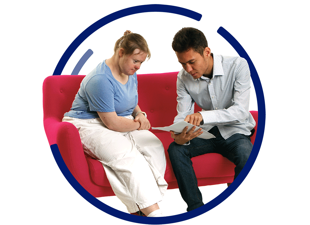 2 people sitting on a couch looking at a document together.